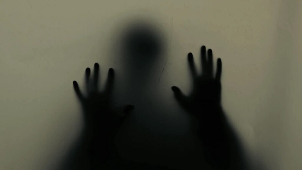 Silhouette aux mains contre une vitre, illustration de la paralysie du sommeil